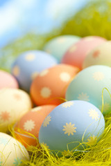 Fototapeta na wymiar Painted Easter eggs in nest on sky background