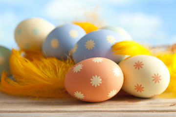 Colorful Easter eggs and feathers on blue background