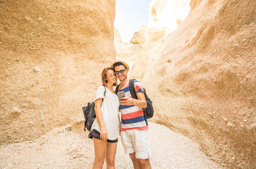 Couple of hikers is smiling looking the smartphone during a trip in the Grand Canyon - caucasian people - people, nature, technology and lifestyle concept