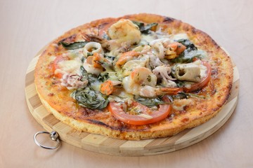 Delicious pizza with seafood on wooden stand
