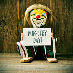old marionette with a signboard with the text puppetry day