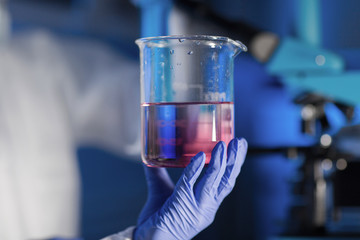 close up of hand holding glass in chemical lab