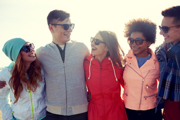 happy teenage friends in shades talking on street