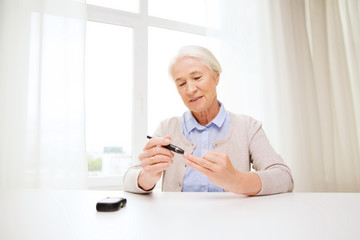 senior woman with glucometer checking blood sugar