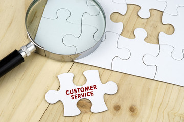 Business concept.Magnifying glass on jigsaw puzzle and a puzzle piece written with CUSTOMER SERVICE...