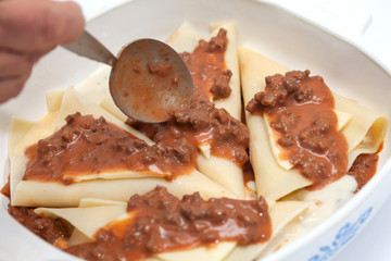Adicionando salsa bolognesa a los triángulos rellenos para lasagna parmesana