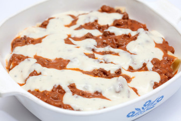 Adicionando salsa blanca a la lasagna parmesana
