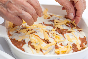 Adicionando quesos a la lasagna parmesana