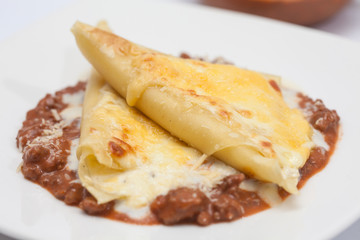 Triángulos de lasagna parmesana servidos sobre salsa bolognesa