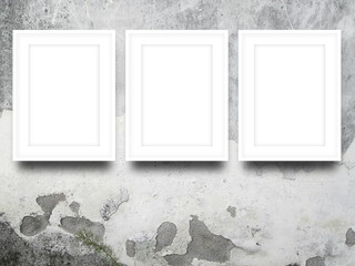 Close-up of three white picture frames on stained concrete wall background