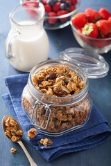 homemade healthy granola in glass jar and berries