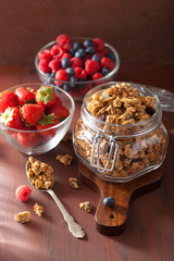 homemade healthy granola in glass jar and berries