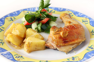 isolated, served homemade baked chicken leg with potatoes and vegetable salad on plate