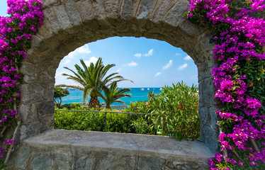 Sea view through the arch framed by bougainvillea