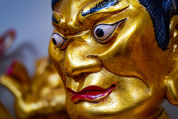 gold colored figure in chinese buddhism temple looking angry with big eyes