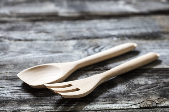 cooking still life - new wooden fork and spoon on genuine wooden background for home-made salad, studio shot