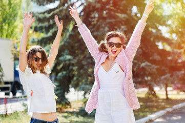 Two young happy women walking in the summer city