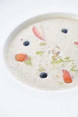 Bowl of delicious breakfast oat and mixed with fruit served in a white ceramic bowl for a healthy nutritious meal