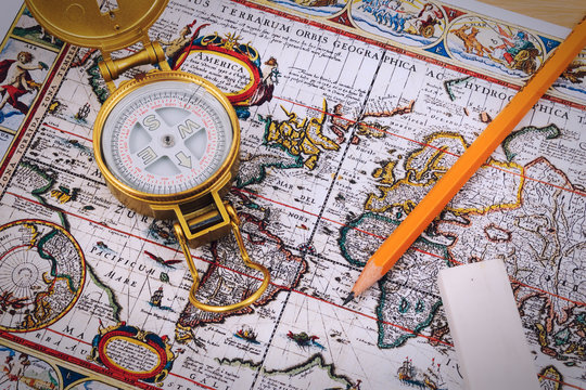Compass and coin with pencil in man hand on vintage paper map.