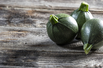 vegetable still life - green round zucchinis set on genuine old wood background for authentic home-made cuisine, studio shot.