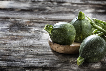 vegetable still life - round zucchinis and green beans set on genuine old wood background for...