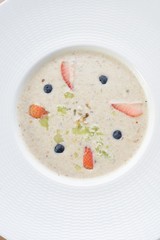 Bowl of delicious breakfast oat and mixed with fruit served in a white ceramic bowl for a healthy nutritious meal