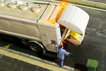 utility service company worker man for cleaning the dumpsters containers of city street in the night