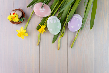 Easter painted eggs on wooden background with .bouquet of daffodils.Top view. Empty space for text.