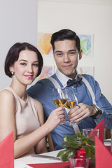 Junges lächelndes Paar stößt mit Rosé in Weingläsern an