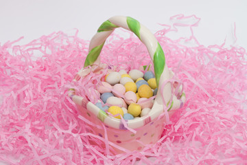 Easter eggs in a ceramic Easter basket and surrounded by pink fake grass