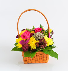 Beautiful flowers in wicker basket on  light background