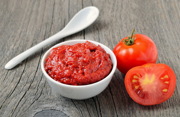Tomato sauce in a white bowl and fresh tomatoes