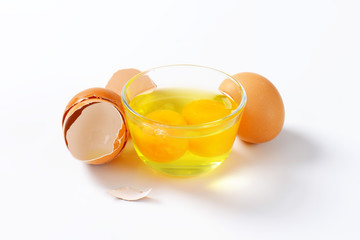 Egg whites and yolks in glass bowl