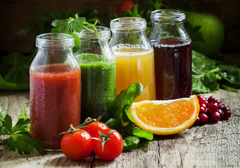 Bottles with fresh juices from fruits and vegetables on an old w