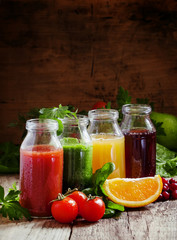 Bottles with fresh juices from fruits and vegetables on an old w