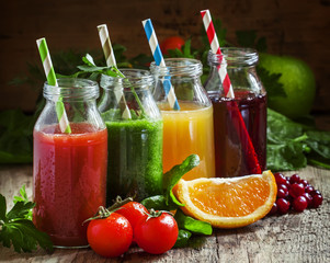 Bottles with fresh juices from fruits and vegetables on an old w