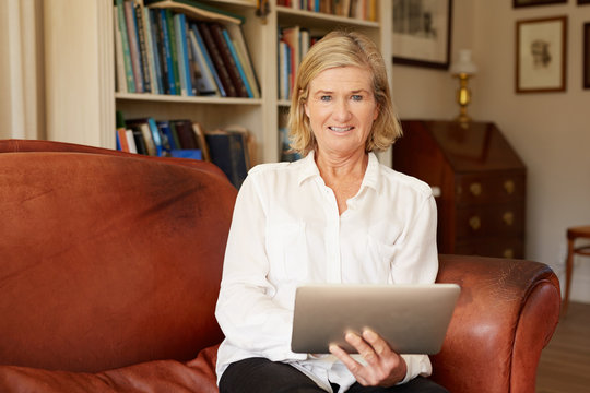 Portrait of a senior woman in living room with tablet