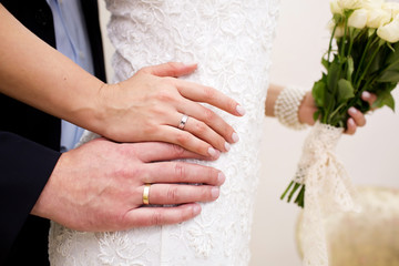 Hands with wedding rings on woman's belly