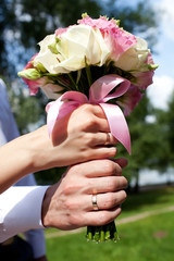 Bride's bouquet in hands with wedding rings