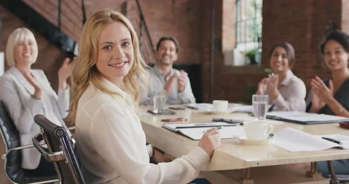 Portrait of a confident young business woman  at boardroom table In slow motion turning around and smiling