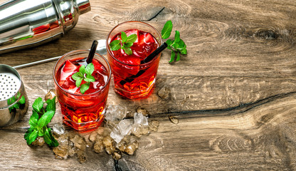 Red cocktail with ice mint leaves on wooden background