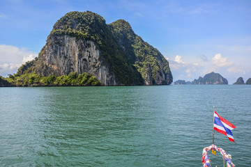 Typical Thailand picture: cliffs in the sea near Phuket with the Thai flag