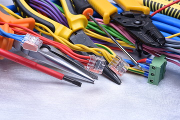 Tools for electrician and cables on grey metal surface