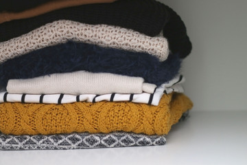 Pile of various sweaters in the closet. Selective focus. 