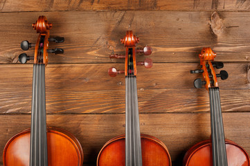 three violins in wood background