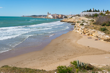 Beach and rocky coast with view of the beautiful town of Sitges,