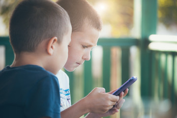 Two little boys playing games on mobile phone
