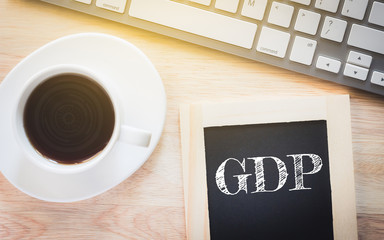 Concept GDP message on wood boards. A keyboard and a glass coffee table.Vintage tone.