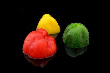 drei halbe paprika in verschiedenen farben auf schwarz