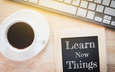 Concept Learn new things message on wood boards. A keyboard and a glass coffee table.Vintage tone.